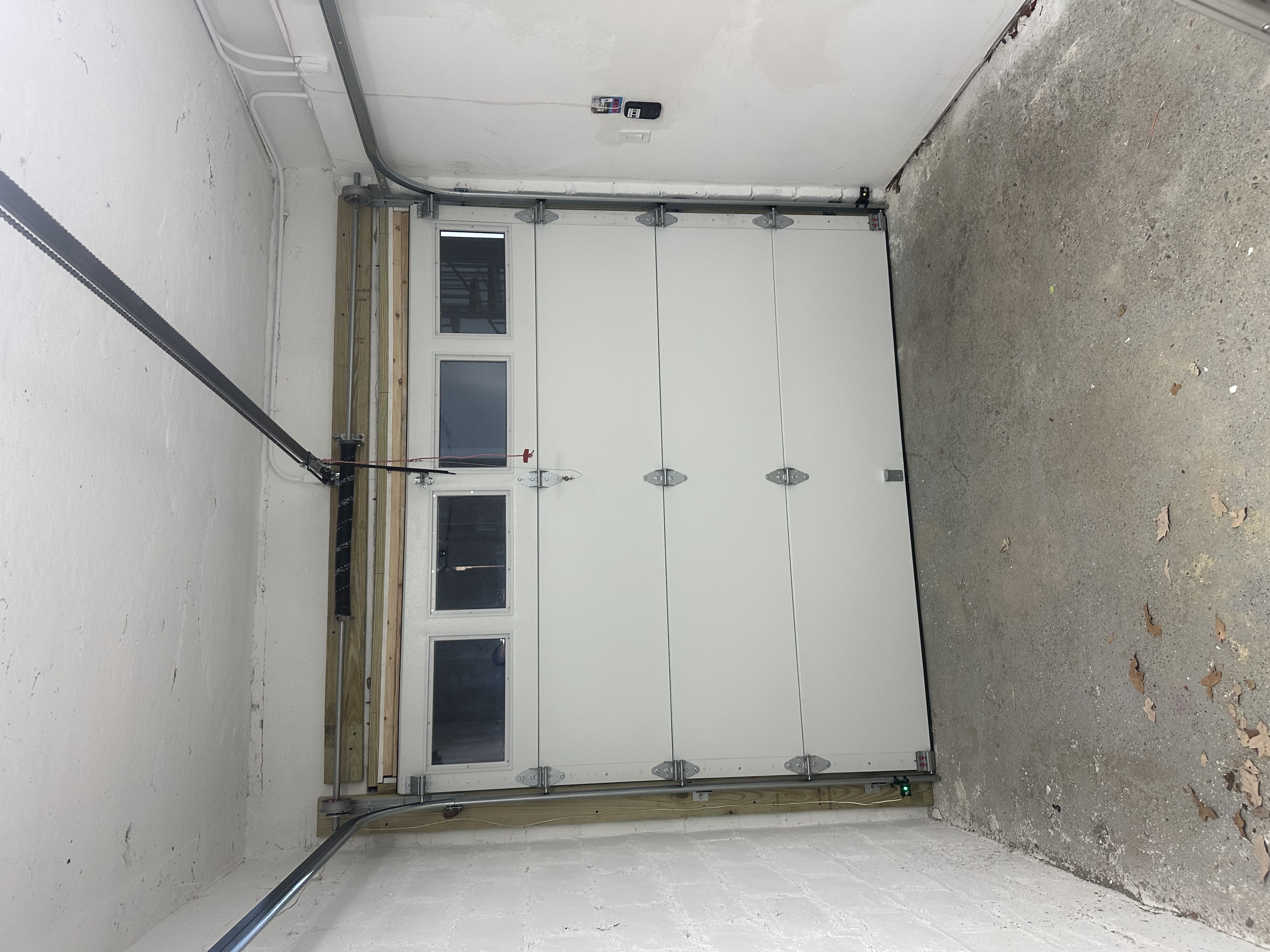 Newly installed white insulated garage door with window panels viewed from inside a residential garage